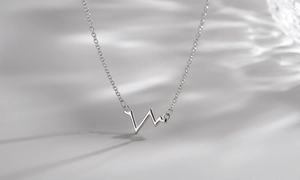 Gros plan du collier pendentif EKG argenté avec reflets de lumière et ondes d'eau