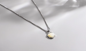 Macro shot of silver box chain necklace featuring an iridescent mother of pearl pendant