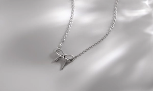 Detailed close-up of a sleek S925 sterling silver bow pendant on a delicate cable chain