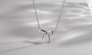 Macro shot of polished silver bow pendant with refined glossy finish and fine link chain