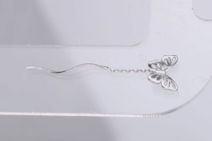 Vue détaillée de la boucle d'oreille papillon en argent avec longue chaîne ondulée et ailes creuses