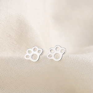 Boucles d'oreilles pattes d'animaux en argent poli avec design évidé sur tissu lin