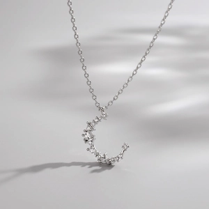 Elegant 925 sterling silver crescent moon necklace with sparkling crystals on light grey background