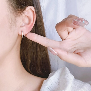 Elegant silver hoop earrings with micro-paved zircons shown in a stylish ear piercing close-up