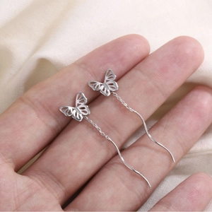 Élégantes boucles d'oreilles papillon avec longues chaînes d'argent sur fond neutre