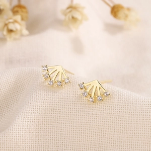 925 silver fan-shaped gold earrings with sparkling zircon stones on a beige linen background