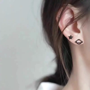 Asymmetric black star and Saturn stud earrings set in a minimalist matte finish
