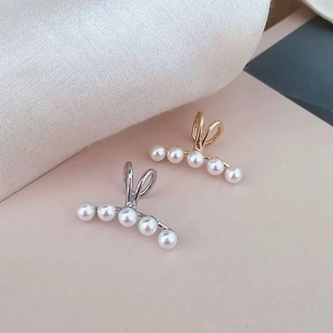 Elegant gold and silver pearl ear bone clips with five white pearls on a pink silk background