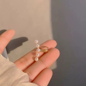 Minimalist gold curved ear cuff with five pearls shown from a side perspective view