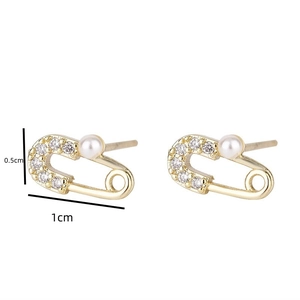 Detail view of gold safety pin earrings with sparkling zircons and white pearls