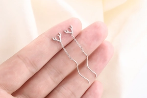 Macro view of sterling silver reindeer antler earrings with delicate wavy chain links