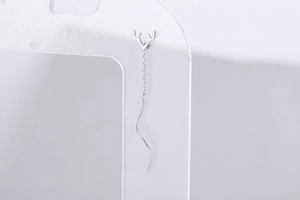 Macro shot of silver antler long drop earrings with tassel chain on display stand