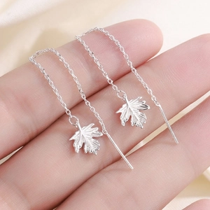Silver leaf tassel threader earrings with maple leaf pendant held on fingertips