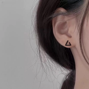 Minimalist geometric triangle stud earrings in matte black finish worn on earlobe