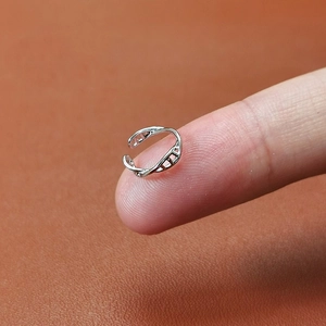 Minimalist silver geometric ear cuff with hollow spiral design shown on fingertip