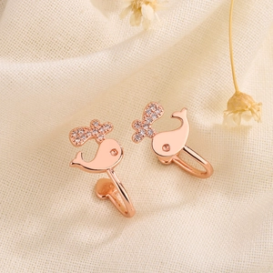 Macro view of rose gold whale ear cuff with cubic zirconia on beige fabric texture