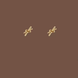 Boucles d'oreilles nœud doré minimaliste pour femmes avec design élégant sur fond marron