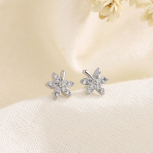 Élégantes boucles d'oreilles fleur à cinq pétales et zircons sur tissu de lin blanc