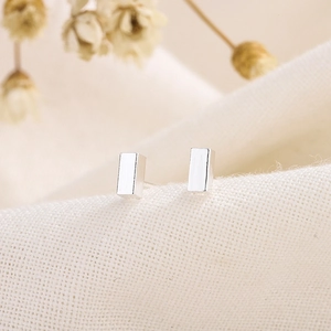 Minimalist silver rectangular stud earrings for men and women on linen background