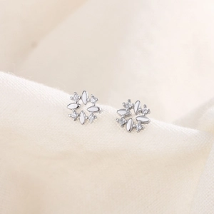 Minimalist silver flower stud earrings with sparkling cubic zirconia on a linen fabric