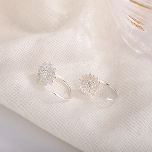 Silver lotus pod hoop earrings with floral texture on soft beige linen background
