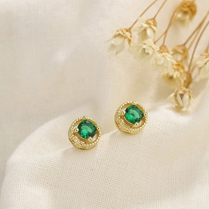 Vintage emerald zircon stud earrings in 18k gold finish on a soft fabric background