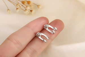 Detailed close-up of minimal silver double-line ball earrings held to show compact size