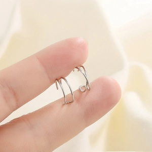 Minimalist silver U-shaped and cross ear cuffs set shown on a hand for sizing