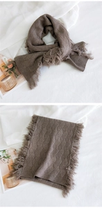 Détail de l'écharpe en maille marron foncé avec motif de losanges et bordures à franges