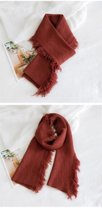 Gros plan d'une écharpe en maille rouge brique avec motifs losanges et longs pompons