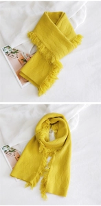 Détail du motif à losanges épais et des franges sur une écharpe d'hiver jaune doux