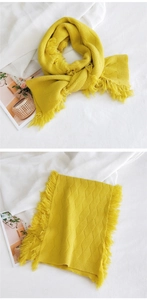 Vue détaillée d'une écharpe en tricot jaune à losanges avec franges douces et texture chaude