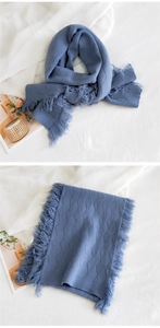 Gros plan sur l'écharpe en tricot bleu avec motif argyle et franges sur fond blanc