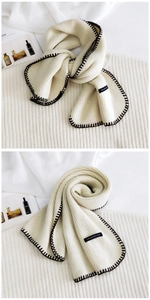 Detail of cream knit scarf featuring black contrast stitching and woven label detail