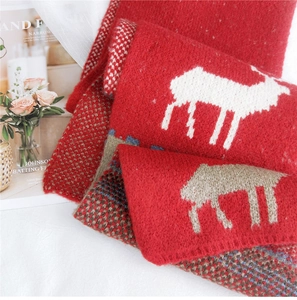 Detailed close-up of soft red knitted Christmas scarf with white reindeer jacquard pattern