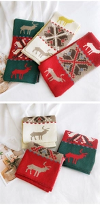 Close-up of knit Christmas scarves with reindeer and snowflake patterns in red and green