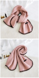 Macro detail of pink knit scarf featuring black contrast stitching and stylish woven label