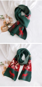 Close-up of dark green Christmas scarf with red reindeer and snowflake knit patterns