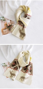 Detail of white knit scarf with brown reindeer pattern and festive geometric border