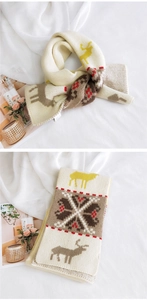 Detail of soft knit texture with reindeer and snowflake patterns on a cream winter scarf
