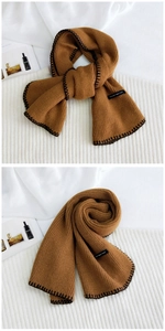 Detailed texture of caramel knit scarf with black stitched edges and fabric brand label