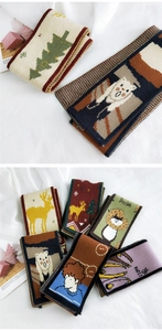 Close-up of soft knit scarves featuring colorful cartoon deer and holiday patterns