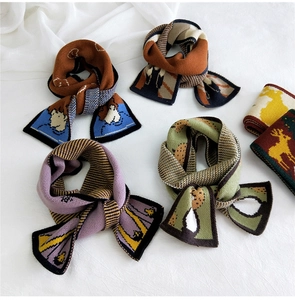 Flat lay of four different colorful knitted cartoon scarves on white fabric background