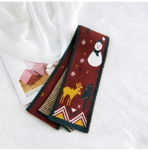 Detail of red Christmas knitted scarf with elk and snowman patterns in soft wool