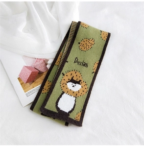 Detail of avocado green knit scarf with cartoon cat patterns and durian texture