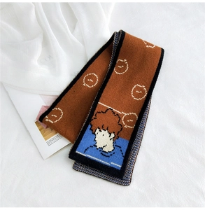 Detailed view of brown knitted scarf with cartoon boy illustration and soft white patterns