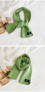 Macro detail of vibrant green ribbed knit scarf with woven brand label and thick texture