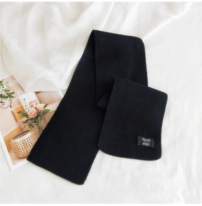 Detailed view of black knitted scarf fabric texture and branded woven label tag
