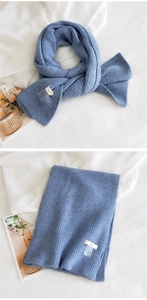 Détail d'une écharpe en tricot bleu montrant la texture rayée et l'étiquette de marque