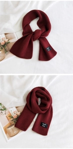 Detail of burgundy ribbed knit scarf with fashion label showing soft texture and drape